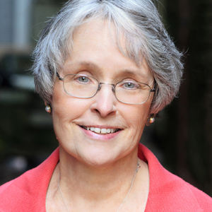 Photo of Betsy Barefoot, wearing glasses and a salmon pink colored top.