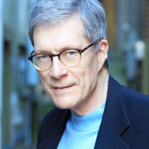 Photo graph of John N. Gardner wearing glasses, a blue jacket with a light blue shirt underneath.