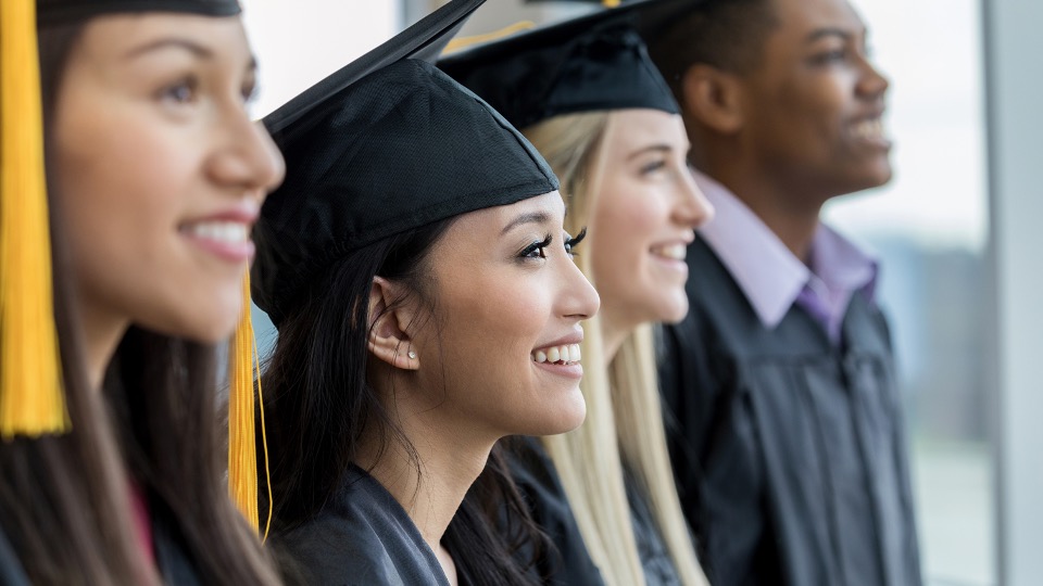 four people wearing graduation caps smiling