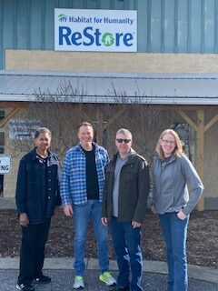 Felita Williams, Drew Koch, Rob Rodier, and Kristen Trader standing outside in front of building with sign above reading Habitat for Humanity Restore