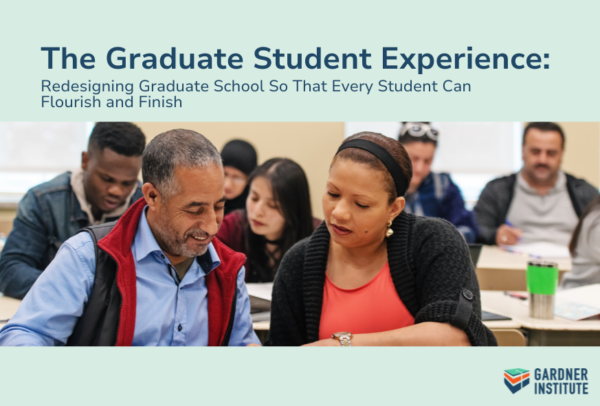 The Graduate Student Experience. Photo of a classroom with male and female adults sitting next to each other at a table in reading together.